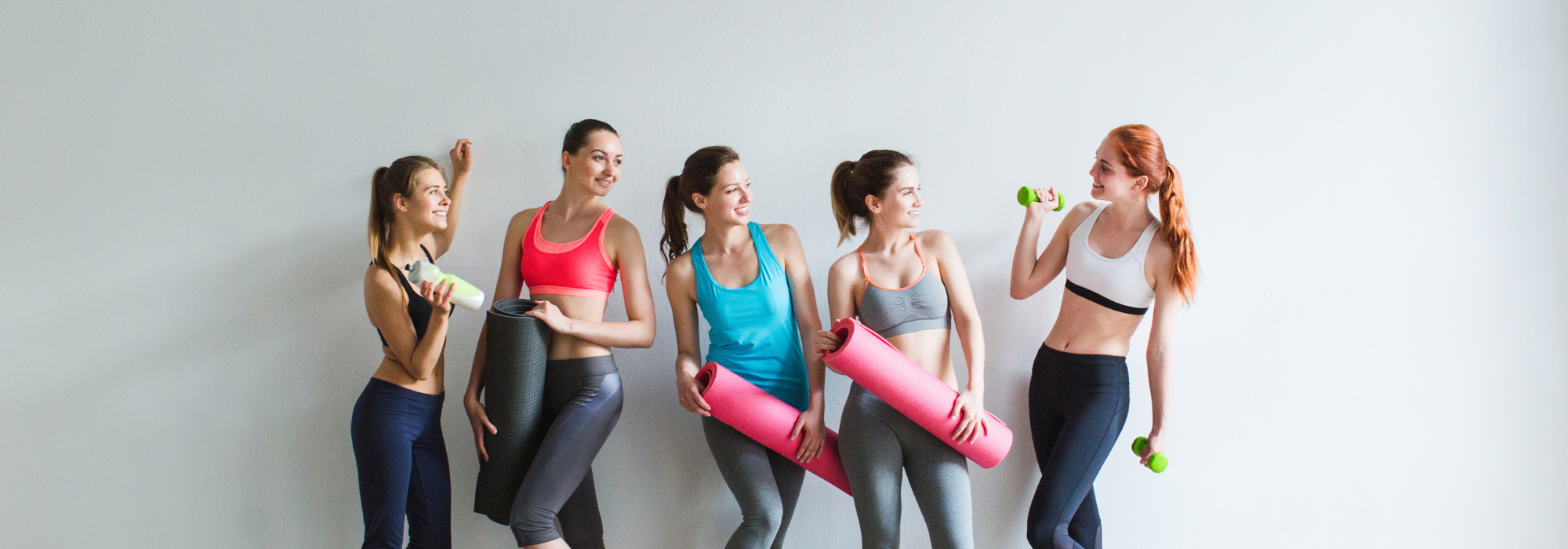 group of women wearing workout clothes with yoga mats